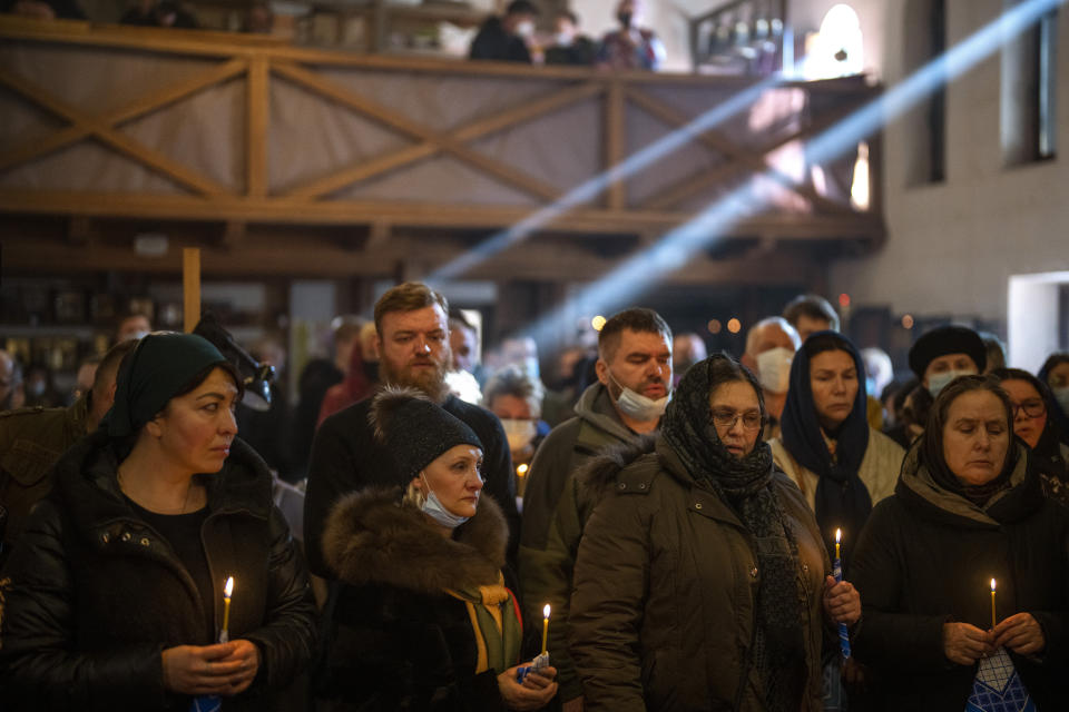 FILE - People pray next to the body of Ukrainian Army captain Anton Sydorov, 35, killed in eastern Ukraine, during his funeral in Kyiv, Ukraine, Tuesday, Feb. 22, 2022. (AP Photo/Emilio Morenatti, File)