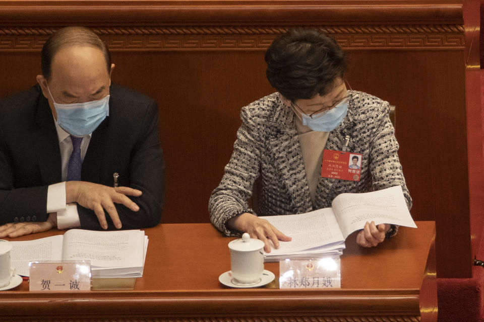 In this photo taken Friday, May 22, 2020, Hong Kong Chief Executive Carrie Lam reads a draft decision on establishing and improving the legal system and enforcement mechanisms for the Hong Kong Special Administrative Region (HKSAR) to safeguard national security submitted to China's national legislature for deliberation during the opening session of the National People's Congress held at the Great Hall of the People in Beijing. China is taking matters into its own hands after months of tumultuous anti-government protests in Hong Kong last year that often descended into tear gas and clashes. In a surprise move, the central government announced that it would develop laws to outlaw secession, subversion of state power, terrorist acts and foreign interference in Hong Kong. (AP Photo/Ng Han Guan)