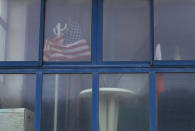 In this photo taken on Thursday, June 4, 2020, French and US flags sit behind a window in a beachfront house near Omaha Beach in Vierville-sur-Mer Normandy, France. In sharp contrast to the 75th anniversary of D-Day, this year's 76th will be one of the loneliest remembrances ever, as the coronavirus pandemic is keeping nearly everyone from traveling. (AP Photo/Virginia Mayo)