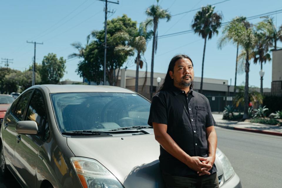 Darren Dela Cruz leans on the hood of his 2008 Prius, whose catalytic converter has been stolen twice.