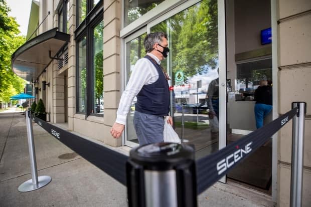 A movie-goer enters a Vancouver theatre after cinemas reopened to the public in British Columbia on Tuesday.  (Ben Nelms/CBC - image credit)