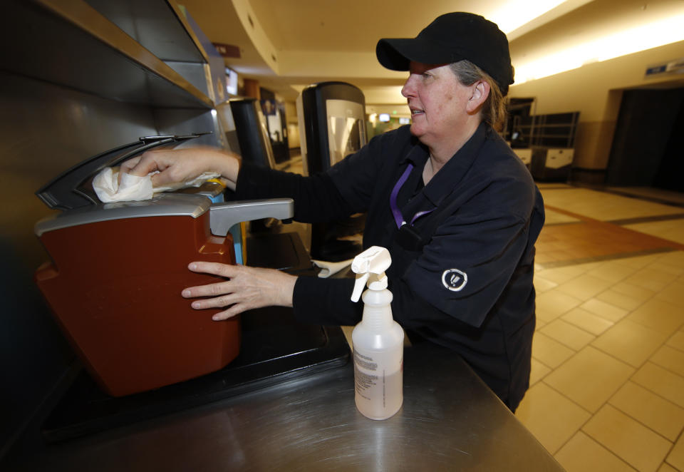 As the cases of Coronavirus spiral upward, Eileen Krause cleans condiment dispensers on the main concourse of Pepsi Center before an NHL hockey game between the New York Rangers and Colorado Avalanche Wednesday, March 11, 2020, in Denver. (AP Photo/David Zalubowski)