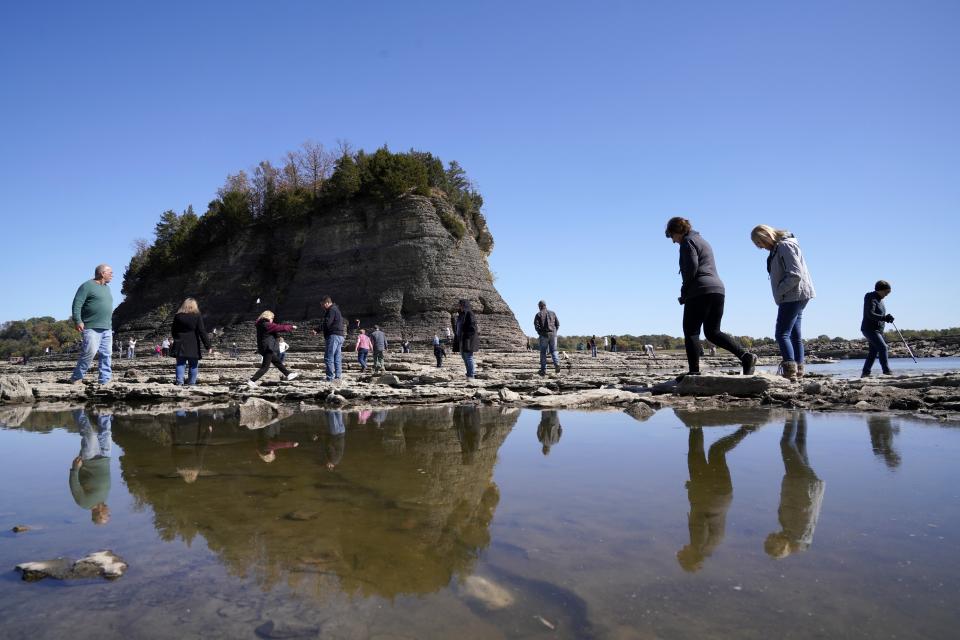 FILE - People walk to Tower Rock, an attraction normally surrounded by the Mississippi River and only accessible by boat, Oct. 19, 2022, in Perry County, Mo. Diverting Mississippi River water to states struggling with water scarcity isn't a new idea. But mayors along the river may soon be voting to support a compact that could block such a diversion. (AP Photo/Jeff Roberson, File)