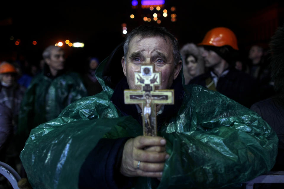 An anti-government protester holds a crucifix as he prays at Independence Square in Kiev, Ukraine, Thursday, Feb. 20, 2014. Ukraine's protest leaders and the president they aim to oust called a truce Wednesday, just hours after the military raised fears of a widespread crackdown with a vow to defeat "terrorists" responsible for seizing weapons and burning down buildings. (AP Photo/ Marko Drobnjakovic)