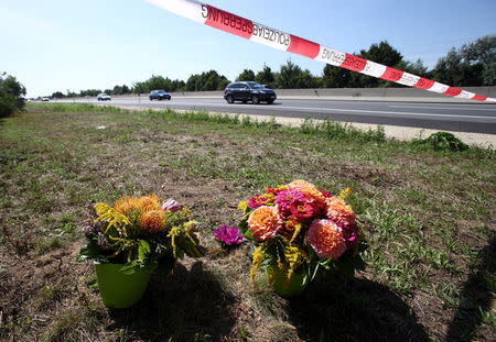 Flowers and candles are placed at the site where a refrigerated truck with decomposing bodies was found by an Austrian motorway patrol near the Hungarian border on Thursday, near Parndorf, Austria, August 28, 2015. REUTERS/Heinz-Peter Bader