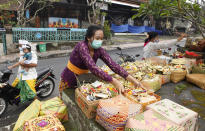 A woman gives an offering as she wears a face mask as a precaution against the new coronavirus outbreak during a Hindu ritual prayer at a temple in Bali, Indonesia, Wednesday, Sept. 16, 2020. (AP Photo/Firdia Lisnawati)