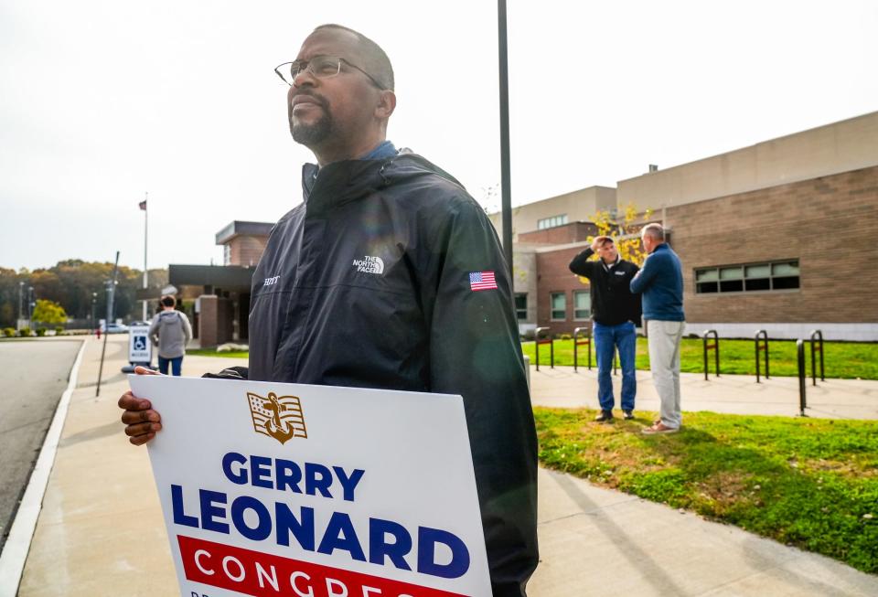 Mark Garmon holds his candidate's sign as Gerry Leonard, right, visits Barrington Middle School polling place.