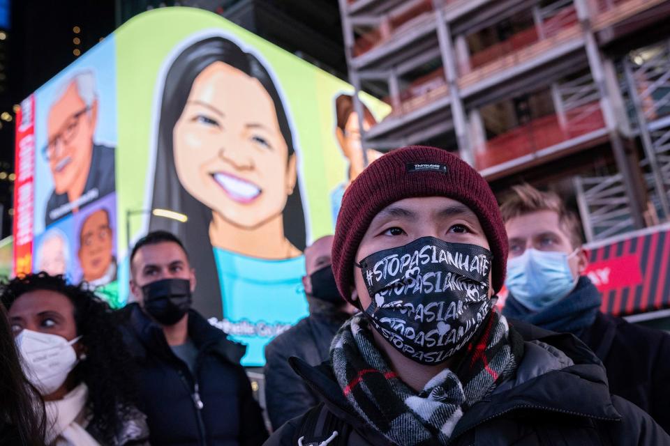 A person wearing a face mask reading, "Stop Asian Hate," attends a candlelight vigil in honor of Michelle Alyssa Go, a victim of a subway attack several days earlier, Tuesday, Jan. 18, 2022, in New York's Times Square. (AP Photo/Yuki Iwamura)