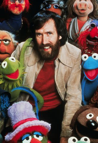 <p>Bettmann</p> Jim Henson poses with his creation characters in The Muppets TV show.