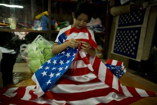 A local woman is seen folding US national flags at a shop in Yangon. The United States on Friday lifted a nearly decade-old ban on most imports from Myanmar, saying it was hoping to encourage recent reforms days before a landmark visit by President Barack Obama