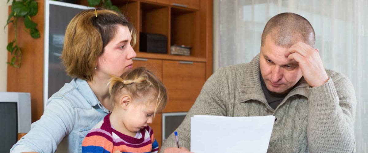 Serious couple with little girl counting budget at home