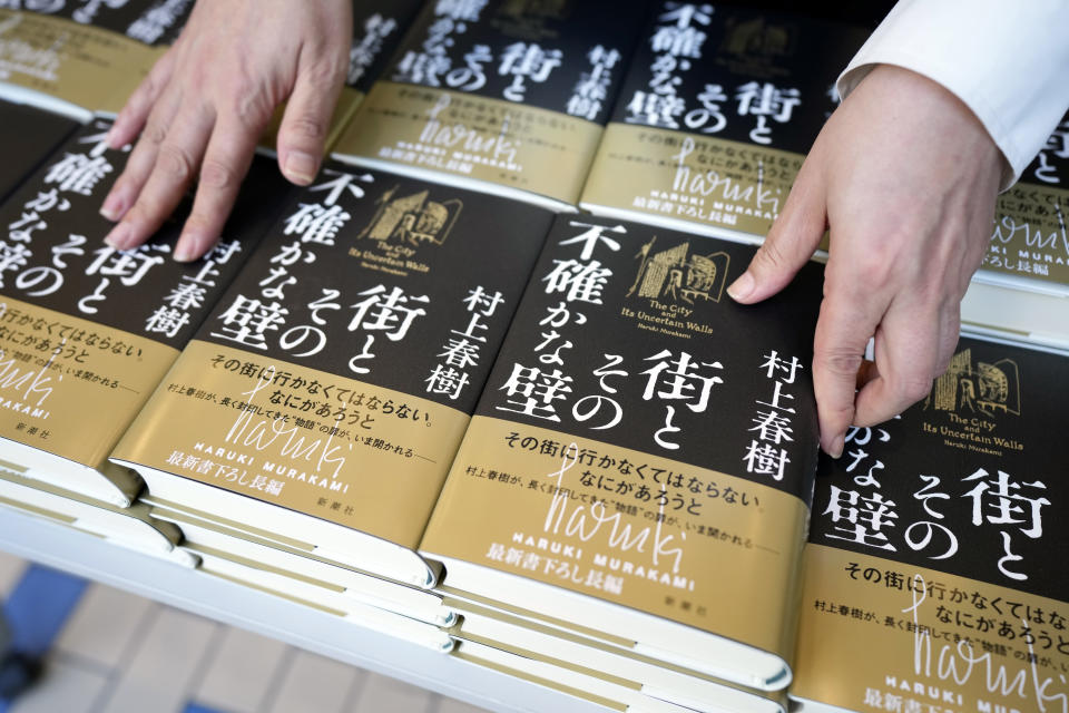 A shop clerk arranges a Japanese writer Haruki Murakami's new novel "The City and Its Uncertain Walls" on the first day for sale at Kinokuniya bookstore in Shinjuku district on early Thursday, April 13, 2023, in Tokyo. Murakami wrote a story of a walled city when he was fresh off his debut. More than four decades later, as a seasoned and acclaimed novelist, he gave it a new life as “The City and Its Uncertain Walls.” (AP Photo/Eugene Hoshiko)