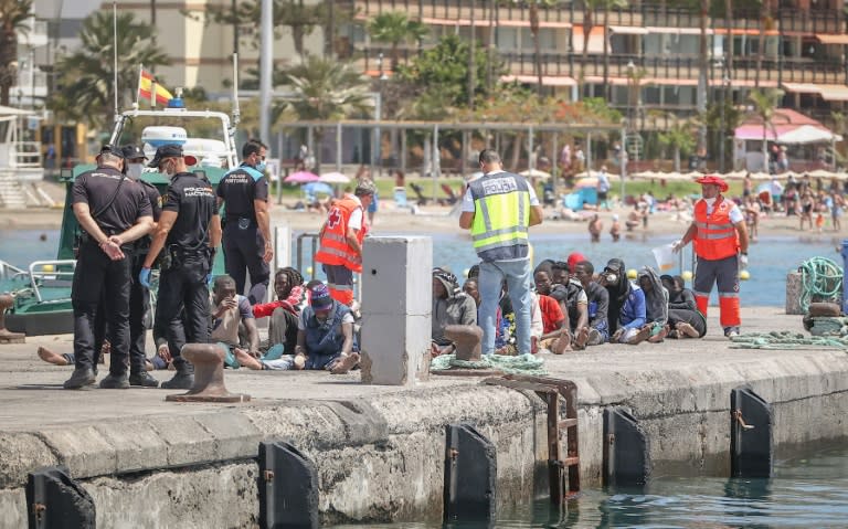 Un grupo de migrantes interceptado por Salvamento Marítimo aguarda sentado en un muelle tras llegar al puerto de Los Cristianos, en la isla de Tenerife, el 8 de mayo de 2024 en el archipiélago español de las Canarias (Desirée Martín)