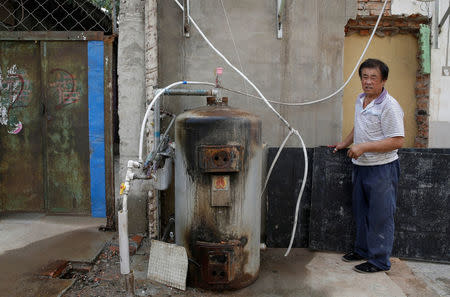 A villager stands next to an abandoned coal-powered boiler in Xiaozhangwan village of Tongzhou district, on the outskirts of Beijing, China June 28, 2017. Picture taken June 28, 2017. REUTERS/Jason Lee