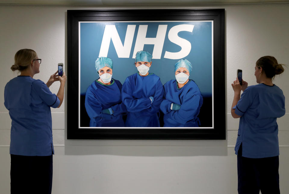 Nurses view a painting by Glasgow artist Robert Miller of three NHS colleagues on the frontline in the fight against Covid-19. It hangs just outside the Intensive Care Unit of Glasgow Royal Infirmary. (Photo by Andrew Milligan/PA Images via Getty Images)