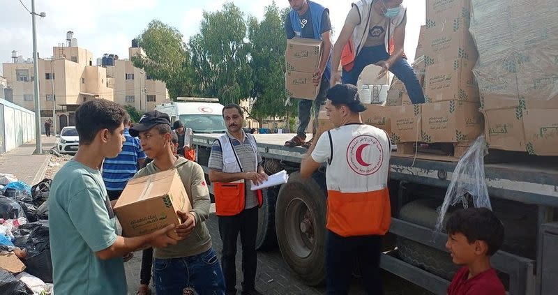 Members of the Palestine Red Crescent Society distribute aid to people in Khan Younis