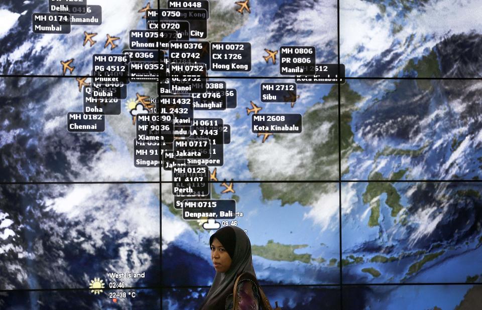 Una mujer pasa enfrente de un tablero electrónico que muestra información de vuelos en el Aeropuerto Internacional de the Kuala Lumpur, Malasia, el domingo 16 de marzo de 2014. Al menos 26 países buscan el avión de Malaysia Airlines desaparecido el 8 de marzo con 239 personas abordo. (Foto AP/Wong Maye-E)