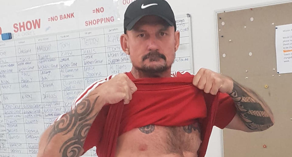 Ben Hoffmann, 45, who allegedly shot four people dead and injured one in Darwin, holds up his shirt. 