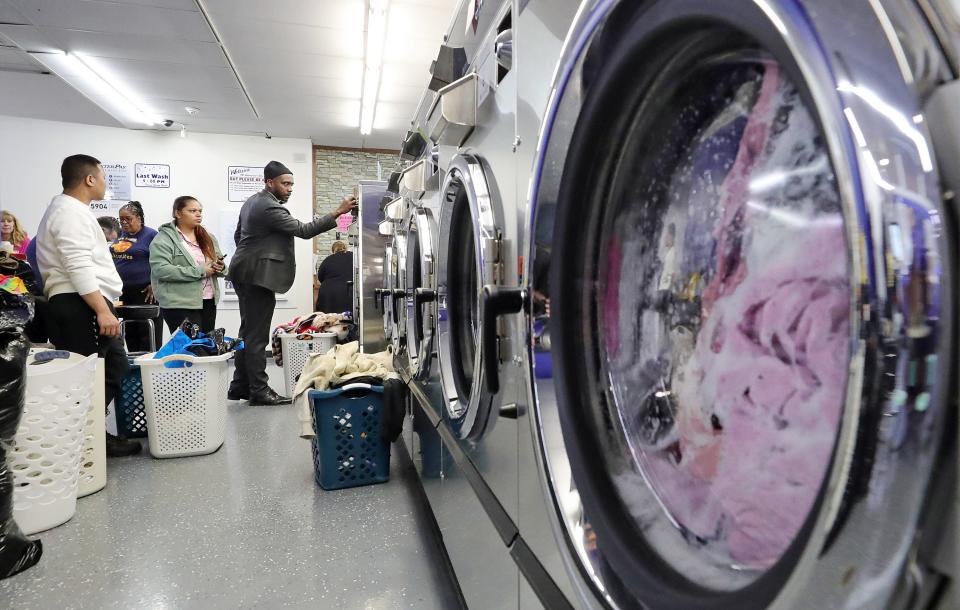 Denico Buckley-Knight, youth opportunity strategist for the city, right, helps Akron residents with their laundry during Tumble Together Thursday at Super Clean Laundromat on Brittain Road.