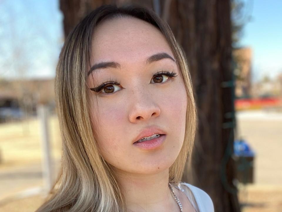 Katherine Pan wearing a white shirt standing in front of a tree on a sunny day