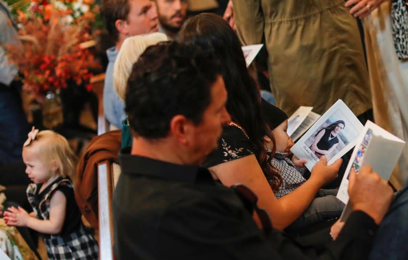 Relatives hold prayer pamphlets with a picture of Christina Marie Langford Johnson, who was killed by unknown assailants, during the funeral service before a burial at the cemetery in LeBaron, Chihuahua