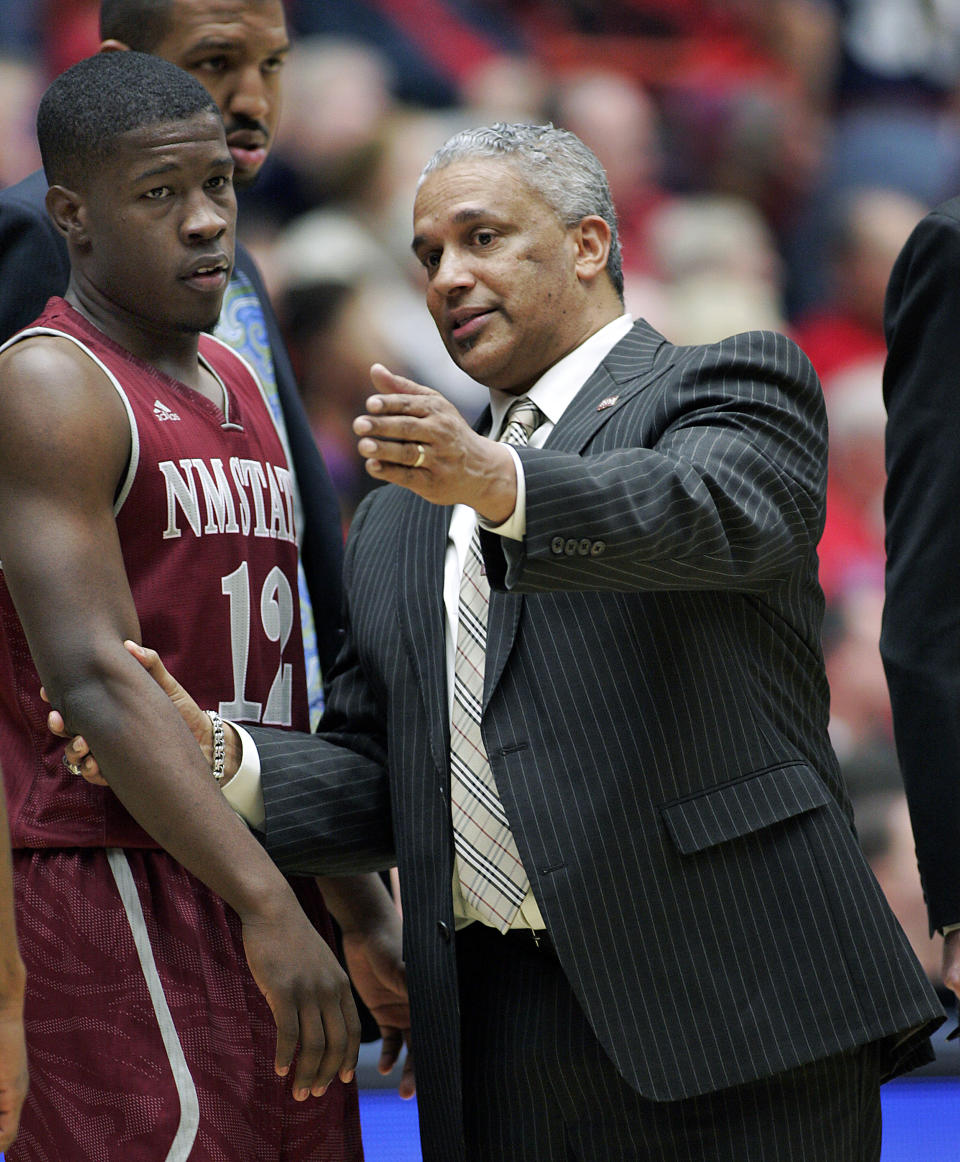 FILE - In this Dec. 11, 2013 file photo, New Mexico States' head coach Marvin Menzies, right, pulls K.C. Ross-Miller (12) aside and talks to him during a time-out in the second half against Arizona in an NCAA college basketball in Tucson, Ariz. Ross-Miller is suspended in the aftermath of a brawl that broke out at the end of the Aggies' game at Utah Valley on Thursday night, Feb. 27, 2014. (AP Photo/John Miller, File)