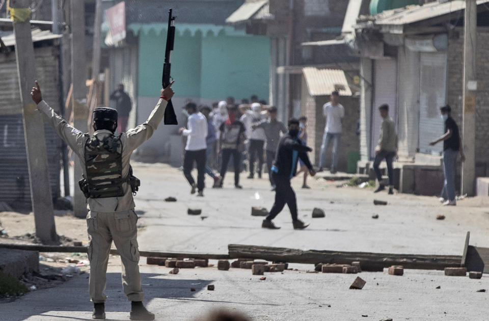 An Indian paramilitary soldier holds up a pellet gun as he challenges Kashmiri protesters marching on the streets in solidarity with rebels engaged in a gunbattle with soldiers, in Srinagar, Indian controlled Kashmir, Thursday, Sept. 17, 2020. The gunfight erupted shortly after scores of counterinsurgency police and soldiers launched an operation based on a tip about the presence of militants in a Srinagar neighborhood, Pankaj Singh, an Indian paramilitary spokesman, said. (AP Photo/Mukhtar Khan)