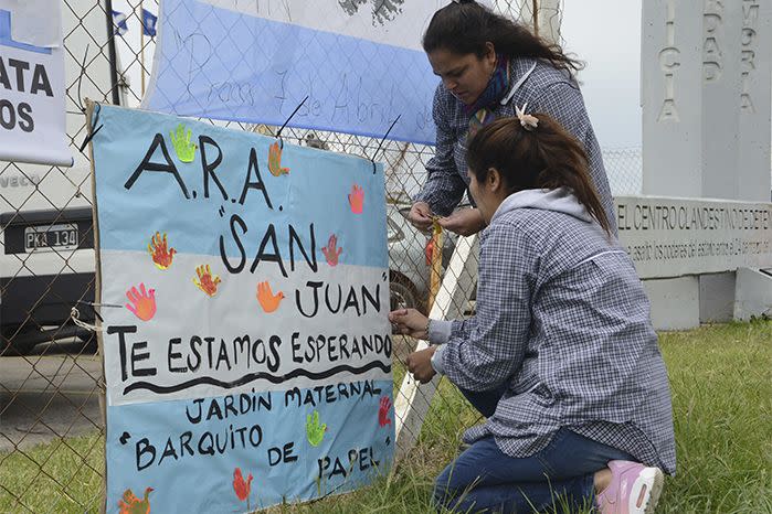 School teachers hang a sign with the colours of the Argentine flag that reads in Spanish 