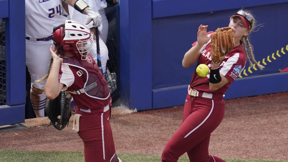 A foul ball hit by James Madison's Logan Newton falls between Oklahoma catcher Kinzie Hansen, left, and third baseman Jana Johns, right, in the seventh inning of an NCAA Women's College World Series softball game Sunday, June 6, 2021, in Oklahoma City. (AP Photo/Sue Ogrocki)
