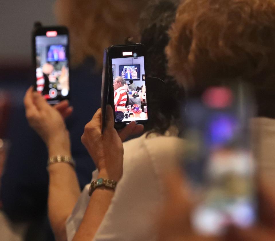 Members of Port Orange VFW Post 3282 record former President Donald Trump with their cell phones who made an unexpected Zoom call to the post, Thursday July 4, 2024.