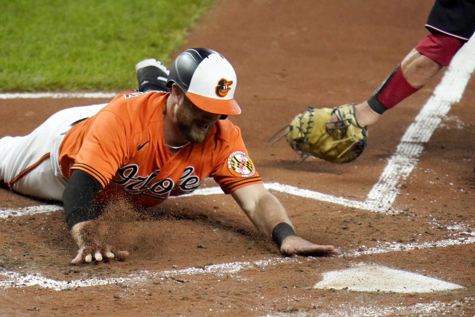 Baltimore Orioles' Bryan Holaday slides head first into home plate ahead of the tag of Washington Nationals catcher Yan Gomes while scoring on a triple by Orioles' Andrew Velazquez during the second inning of a baseball game, Saturday, Aug. 15, 2020, in Baltimore. (AP Photo/Julio Cortez)