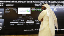 A Saudi stock market official smiles as he watches the stock market screen displaying Saudi Arabia's state-owned oil company Aramco after the debut of Aramco's initial public offering (IPO) on the Riyadh's stock market in Riyadh, Saudi Arabia, Wednesday, Dec. 11, 2019. (AP Photo/Amr Nabil)