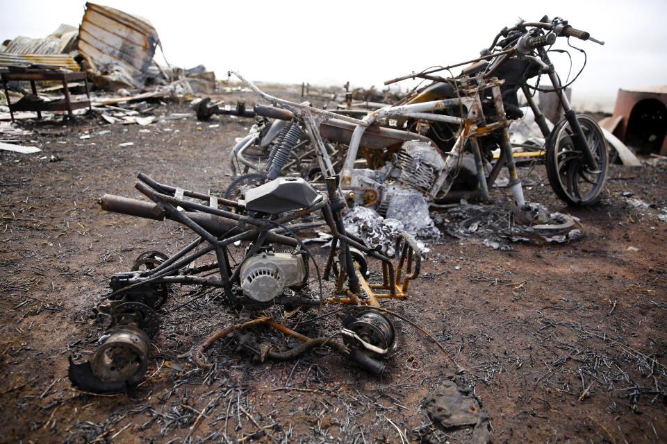 Motorcycles and an ATV destroyed by wildfire sit on Joshua Kihe's property near Waimea, Hawaii, Wednesday, Aug. 4, 2021. The area was scorched by the state's largest ever wildfire. (AP Photo/Caleb Jones)