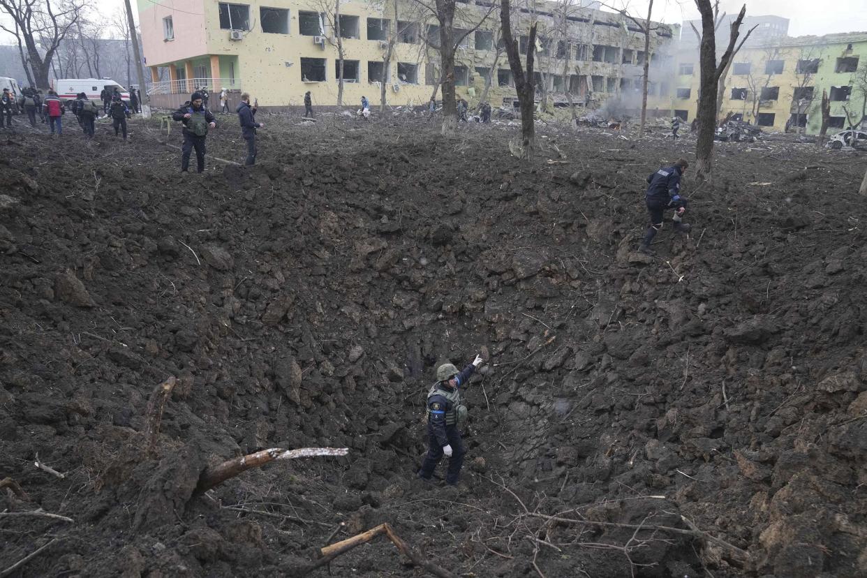 Ukrainian soldiers and emergency employees work at the side of the damaged by shelling maternity hospital in Mariupol, Ukraine, Wednesday, March 9, 2022.