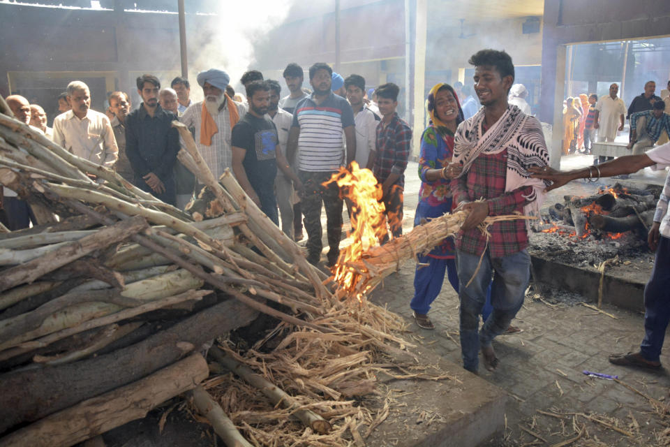 Gurjeet Kumar lights the funeral pyre of his maternal grandfather, who was killed in Friday's train accident, as his mother holds on to him in Amritsar, India, Saturday, Oct. 20, 2018. A speeding train ran over a crowd watching fireworks during a religious festival in northern India on Friday evening, killing more than 50 people and injuring dozens more, police said. (AP Photo/Prabhjot Gill)