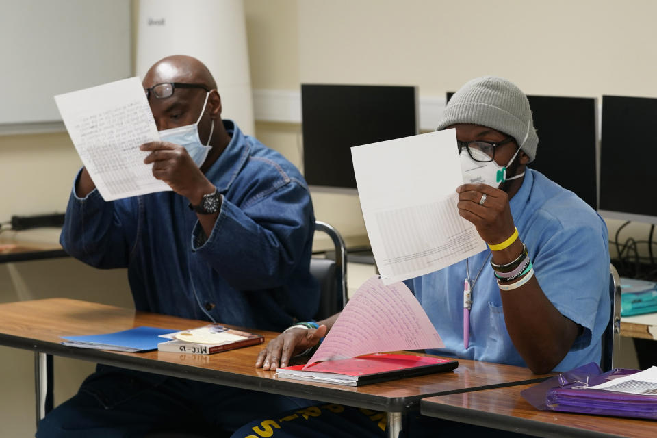 Incarcerated students look at the photograph "The Falling Man," that was part of a discussion during a Mount Tamalpais College English class called Cosmopolitan Fictions at San Quentin State Prison April 12, 2022, in San Quentin, Calif. The community college, the first in California with a campus inside a prison, is the latest addition to San Quentin's numerous rehabilitation programs that have made it a desired destination for inmates throughout the state. (AP Photo/Eric Risberg)