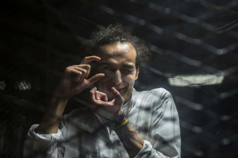 Egyptian photographer Mahmoud Abdel Shakour, known as Shawkan, gestures from inside a soundproof glass dock, during his trial in Cairo on August 9, 2016