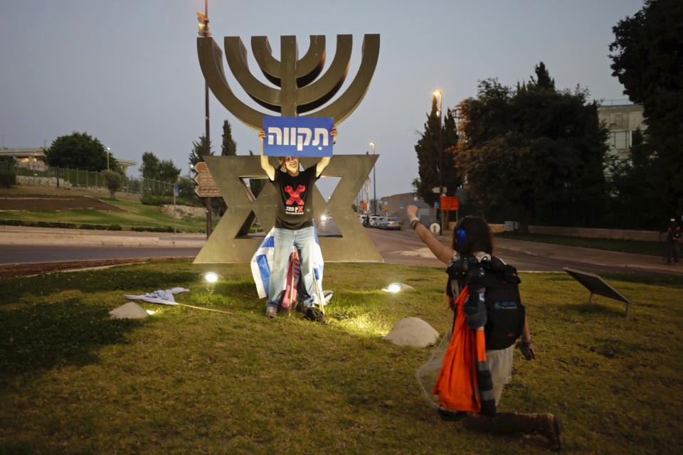 An Israeli protester holds a sign during a demonstration in support of the new government, outside the Knesset, Israel's parliament, in Jerusalem, Sunday, June 13, 2021. Hebrew reads: "Hope." (AP Photo/Sebastian Scheiner)