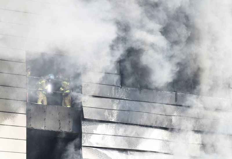 Firefighters search for survivors as smoke rises from a warehouse which is currently under construction, after it caught fire, in Icheon