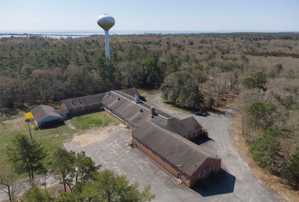 The old Cotuit Elementary School, now vacant, adjacent to a water tower for the Cotuit Fire District. The district voted on May 4 to hold off on demolishing and commissioning a study to see if it can be reused.