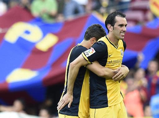 El mediocentro del Atlético de Madrid Koke (I) abraza a su compañero uruguayo Diego Godín, en la consecución del título de su equipo, tras empatar 1-1 ante el Barcelona, el 17 de mayo de 2014 (AFP | LLUIS GENE)