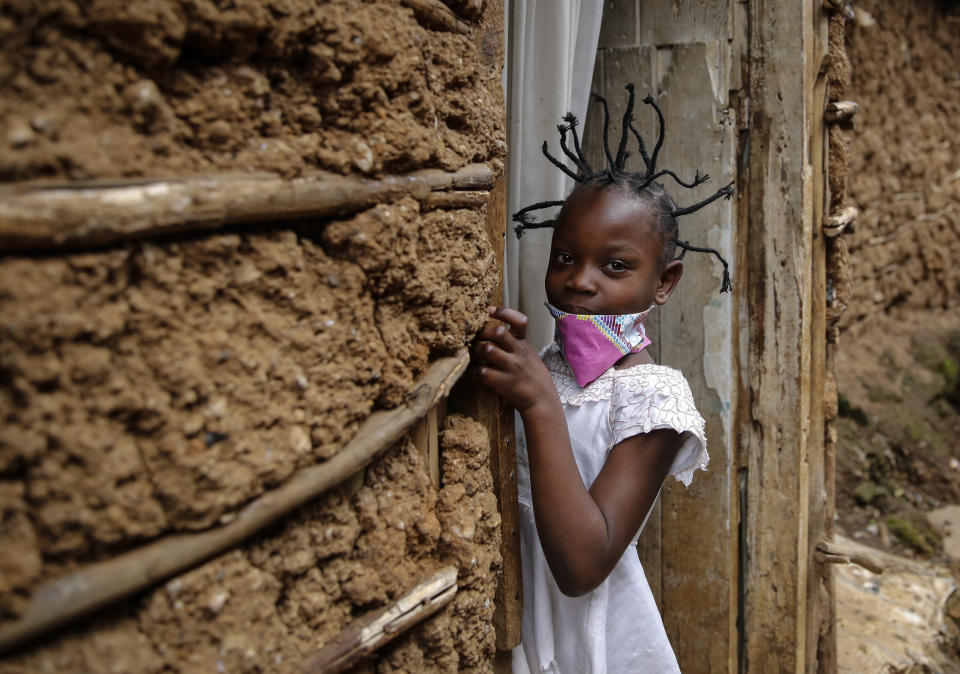 FILE - In this Sunday, May 3, 2020 file photo, Jane Mbone, 7, arrives home after having her hair styled in the shape of the new coronavirus at the Mama Brayo Beauty Salon in the Kibera slum, or informal settlement, of Nairobi, Kenya Sunday, May 3, 2020. The coronavirus has revived a hairstyle in East Africa, one with braided spikes that echo the virus' distinctive shape, with the growing popularity in part due to economic hardships linked to virus restrictions. (AP Photo/Brian Inganga, File)
