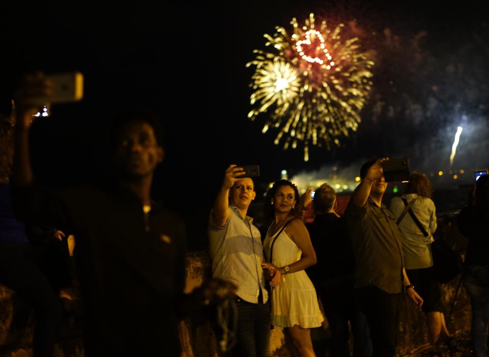 People take selfies at the malecon watching the fireworks as part of the celebration of the 500 years of the city in Havana, Cuba, Friday, Nov. 15, 2019. Havana celebrate its 500th anniversary on Saturday, a milestone event which has sparked reflection and anticipation in the country, as it faces an increasingly hostile US Administration and serious economic challenges. (AP Photo/Ramon Espinosa)