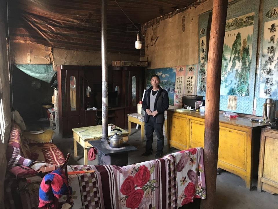 Yang Jiacun, who does construction work in Xinjiang, stands in the village home where his parents still live.