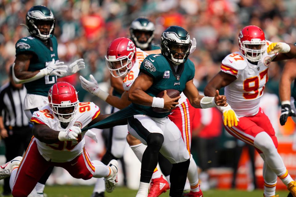 Philadelphia Eagles quarterback Jalen Hurts (1) runs with the ball as Kansas City Chiefs defensive tackle Jarran Reed (90) holds on to part of Hurts' uniform during the first half of an NFL football game Sunday, Oct. 3, 2021, in Philadelphia.