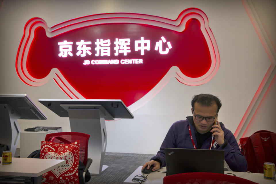 A worker talks on his cellphone as he uses his laptop computer at the command center at the headquarters of e-commerce retailer JD.com in Beijing, Sunday, Nov. 11, 2018. Online shoppers spent more than $14 billion within the first two hours of China's annual buying frenzy on Sunday, once again breaking records as the consumer tradition enters its 10th year. (AP Photo/Mark Schiefelbein)