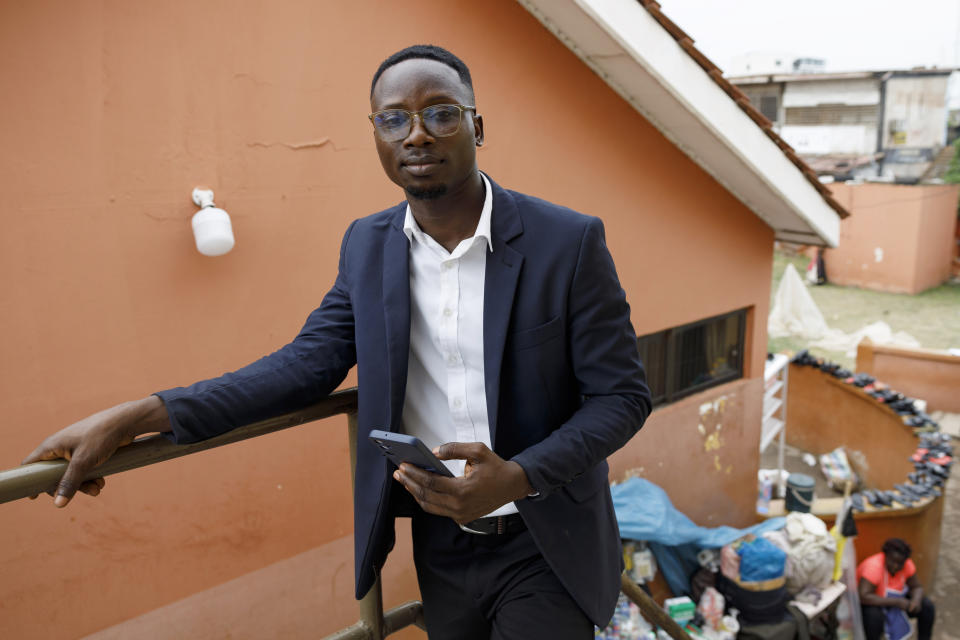 Shadrach Damateye, a co-founder of Masters Hive Center for Innovation, who uses his mobile phone to help business owners, poses for a photograph outside his office in Tema, Ghana, Tuesday, April 23, 2024. Internet-enabled phones can play a unique role in sub-Saharan Africa, where infrastructure and public services are among the world’s least developed. But despite growing mobile internet coverage on the continent of 1.3 billion people, just 25% of adults in sub-Saharan Africa currently have access to it. (AP Photo/Misper Apawu)