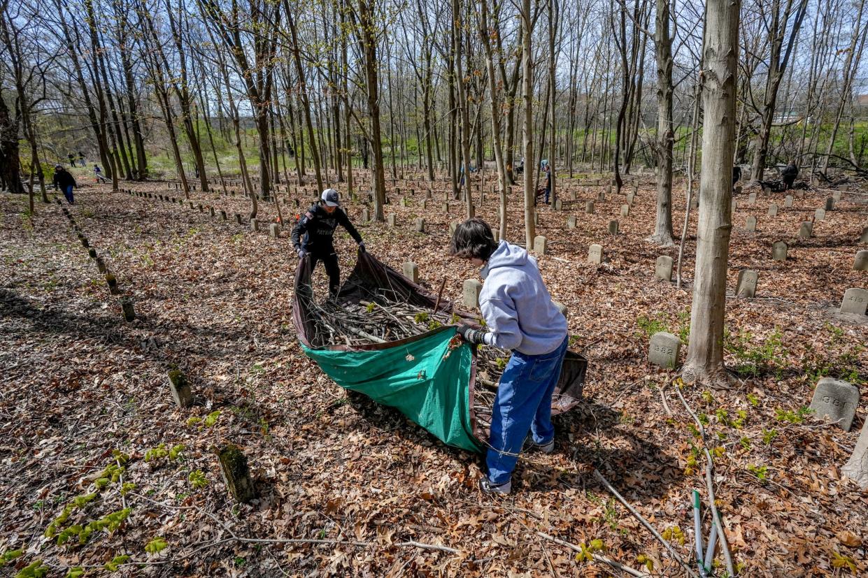 Chase Preble and Ben Ferrara of Somerset Berkley Regional High School in Massachusetts help clear brush and debris during Saturday's cleanup of the State Farm Cemetery Annex grounds next to the Rhode Island Training School in Cranston.