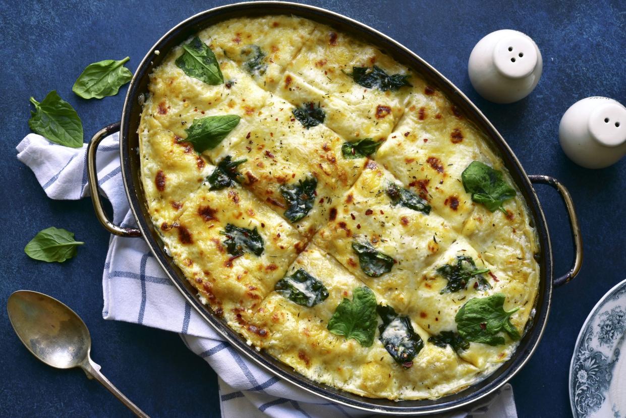 Homemade delicious chicken mushroom spinach lasagna in a baking dish on a dark blue slate, stone or concrete background.Top view with copy space.