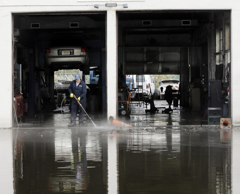 Steve Formica washes a garage bay at Chizzy's Truck and Auto Repairs in the wake of superstorm Sandy on Thursday, Nov. 1, 2012, in Little Ferry, N.J. Surprise coastal surge floods caused by the storm battered Little Ferry, Moonachie and some other towns along the Hackensack River in Bergen County _ all areas unaccustomed to flooding. (AP Photo/Mike Groll)